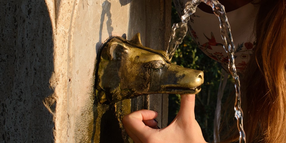 Doigt bouchant la sortie principale d’une fontaine de la Villa Pamphilj pour diriger l’eau vers le petit orifice supérieur